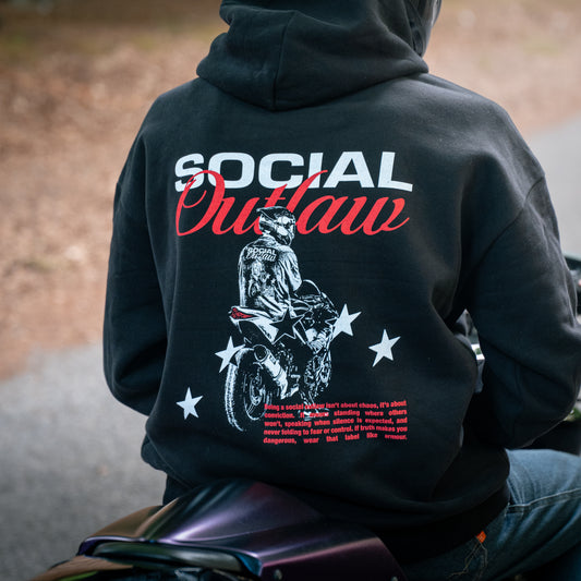 Person wearing a black hoodie with 'Social Outlaw' design sitting on a motorcycle.